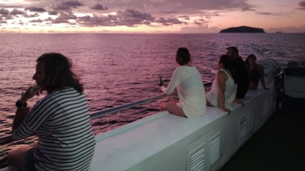 Divers taking a quiet drink on the upper deck of Galapagos Master as the sun sets over the Pacific.