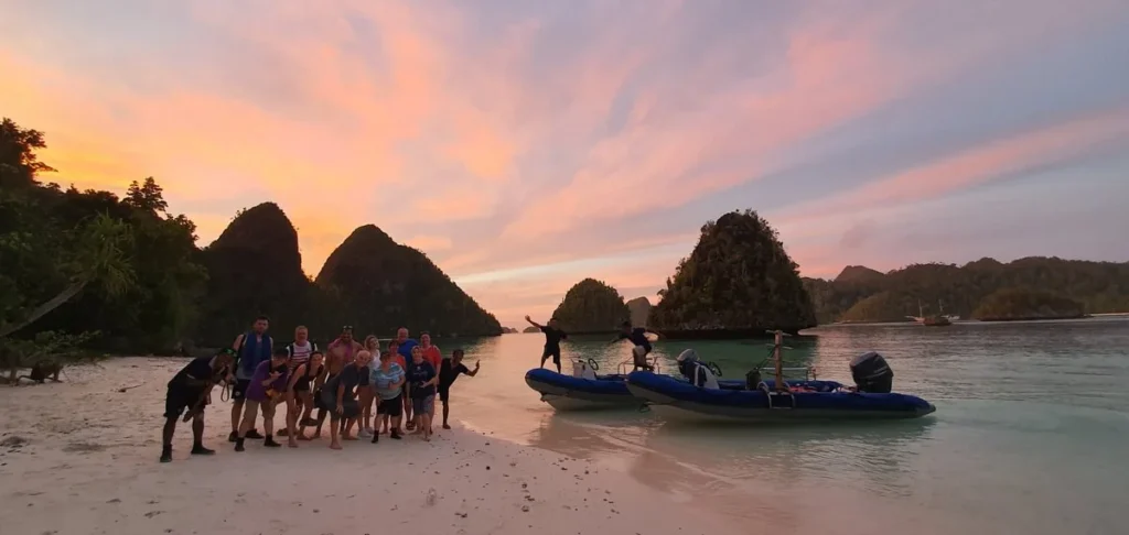 Crew and guests from Indo Master enjoying sunset on a Raja Ampat beach after a day of diving.