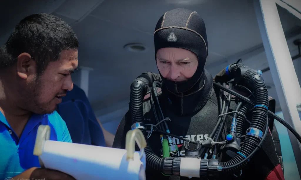 Technical diver on the liveaboard dive platform reviewing dive plan with crew