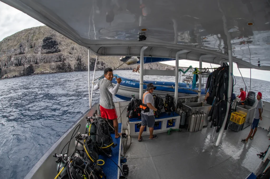 Rows of scuba tanks and hanging wetsuits on a clean, organized dive deck of a Master Liveaboards boat, ready for the morning dive.