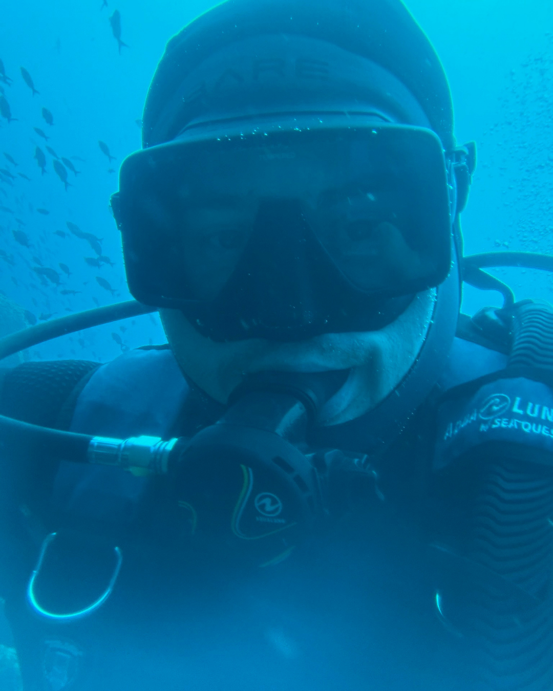 Scuba diver underwater among schooling fish in the Galapagos