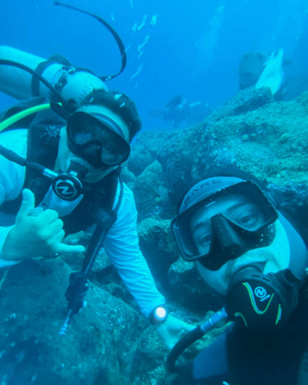 Two scuba divers at a rocky Galapagos dive site