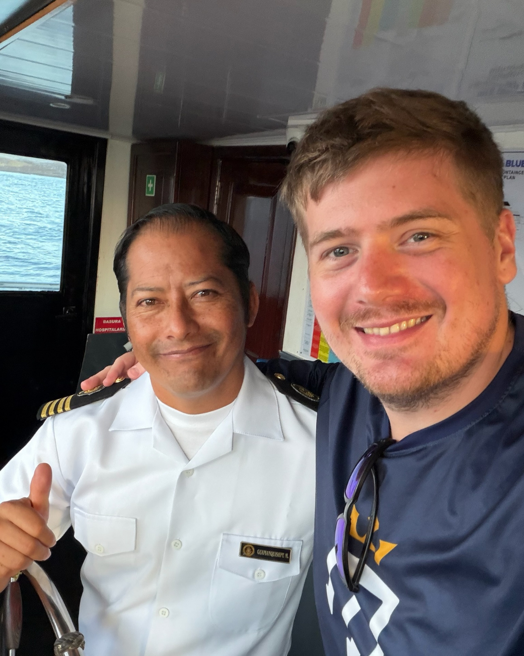 Galapagos Master guest with the captain at the helm